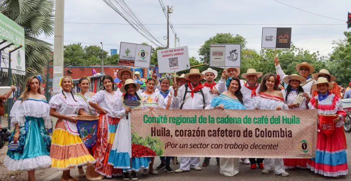 Integrantes del Comité Regional de la Cadena de Café, productores cafeteros y representantes de OIT, posan en el desfile folclorico departamental en la ciudad de Neiva, Huila, usando trajes típicos con el cartel “Comité Regional de la Cadena de café del Huila. Huila, corazón cafetero de Colombia. ¡Por un sector con trabajo decente!”