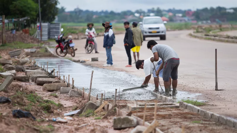 local workers pouring concrete to make a pavement in Lao