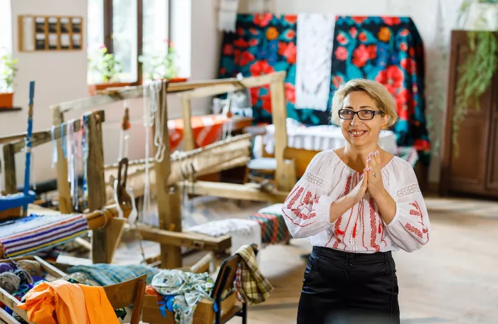 A women standing by a sewing machine in her embroidery workshop.