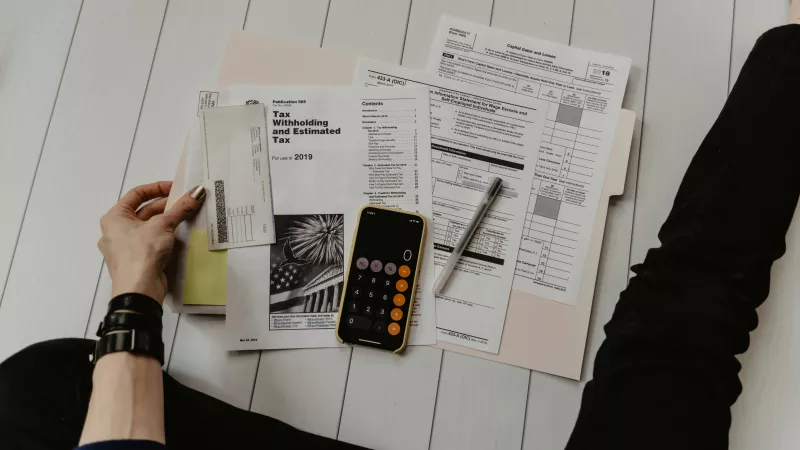 Person holding pen near papers and calculator