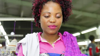 A garment employee stands at her workstation in a clothing factory in Lesotho.